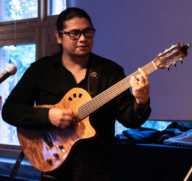 Luis Gato Lincheo playing an acoustic guitar on stage