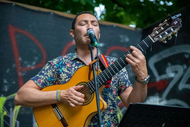 Pablo Gómez singing while playing guitar outdoors